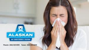 woman blowing nose into tissue with Alaskan Air Conditioning and Heating logo and contact phone numbers